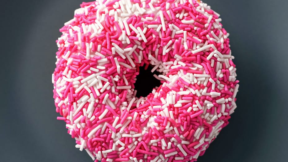EIn Donut mit Pinken und weißen Streußeln.