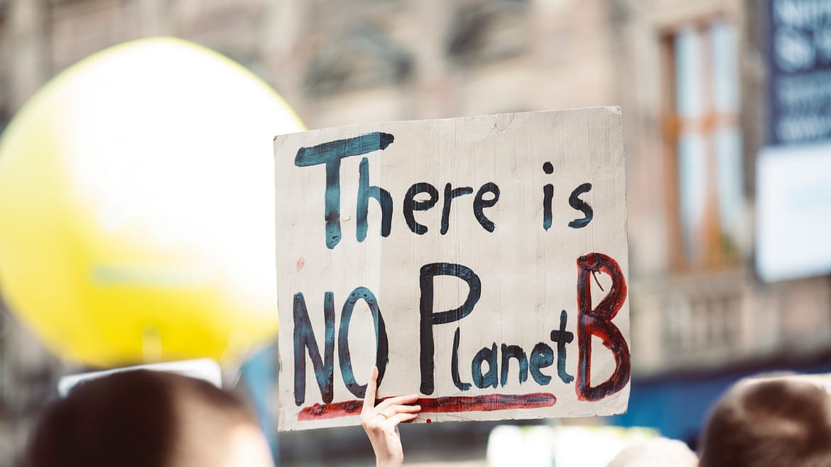 Demonstration, im Vordergrund ein Schild mit Aufschrift "There is NO planet B"