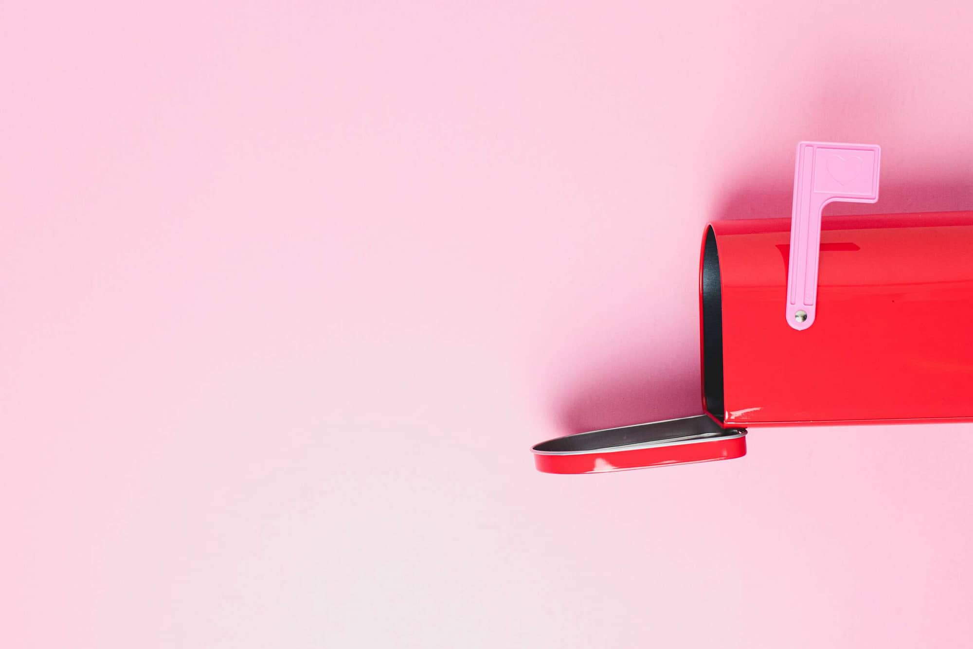 geöffneter roter Briefkasten vor rosa Hintergrund